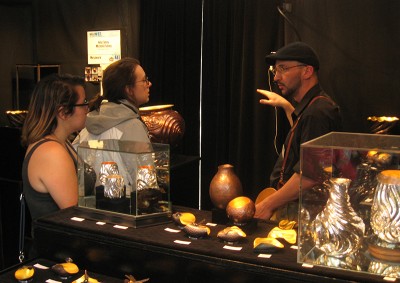 Ashley Smith and Kaitlyn Brown visit with a jewelry/metal artist at the Fort Worth Arts Festival.